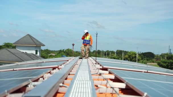 Ázsiai férfi villanyszerelő mérnök ellenőrzi telepítés napelemek fém tetőn ipari gyár séta körül holding power drill ellenőrzés fontos pontok minden napelem a vágólapon. - Felvétel, videó