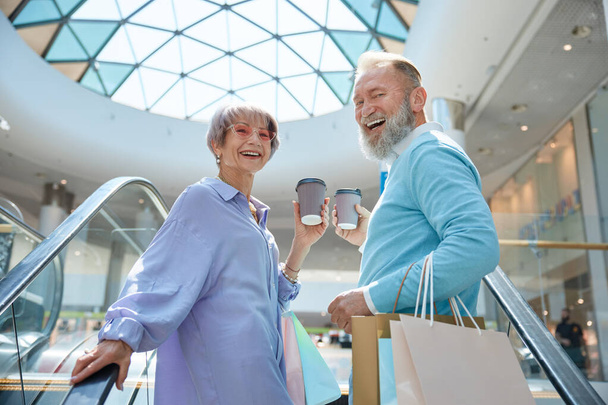 Felnőtt nyugdíjas pár vásárlásokkal, akik jól érzik magukat a bevásárlóközpontban. Hétvégék a nyugdíjazási koncepcióról - Fotó, kép