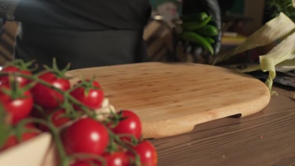 Chef en guantes lanzando pimientos sobre tabla de cortar junto a tomates, hierbas y verduras. cámara lenta, primer plano. - Imágenes, Vídeo