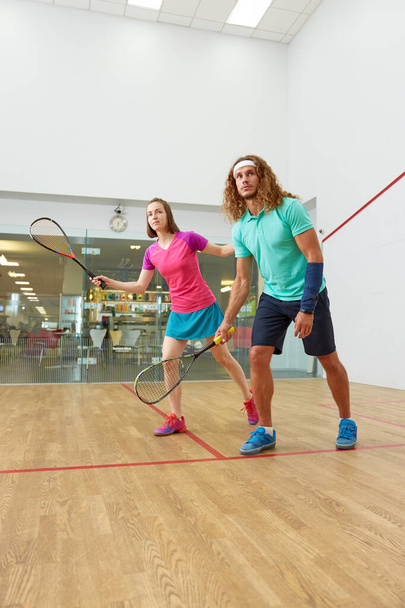 Jovens jogando squash desfrutando de perseguição recreativa no clube de treinamento indoor. Atividade de lazer casal no fim de semana - Foto, Imagem