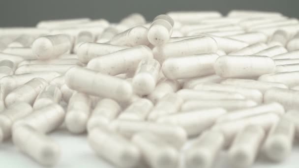 Valkoiset lähikapselit, joissa on vitamiineja ja lääkkeitä, osoittavat ennaltaehkäisevän lääketieteen ja ravintolisien merkityksen. Vitamiinit ja lääkkeet liikkeessä: lääketeollisuus toiminnassa - Materiaali, video