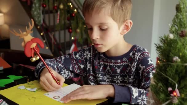 Szekrény a kisfiúról, aki levelet ír a Mikulásnak egy karácsonyi díszítésű nappaliban.. - Felvétel, videó