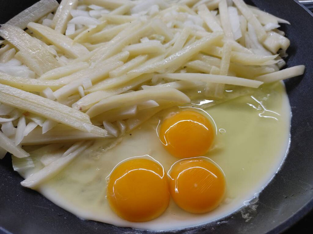 Cucinare uova strapazzate e patate fritte in una padella di teflon nero - Foto, immagini