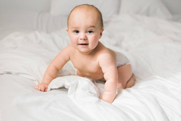 Gelukkige baby ligt lachend op bed. Generatie alfa en gen alfa. - Foto, afbeelding