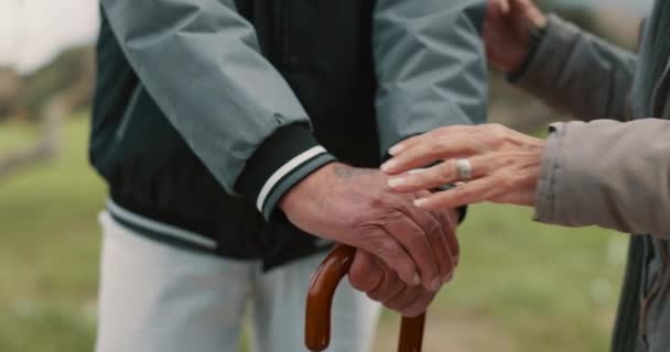 Hands, cane and senior couple in nature for walking together for fresh air or peace in a park. Environment, closeup and elderly man and woman in retirement with a stick for support in outdoor garden - Footage, Video