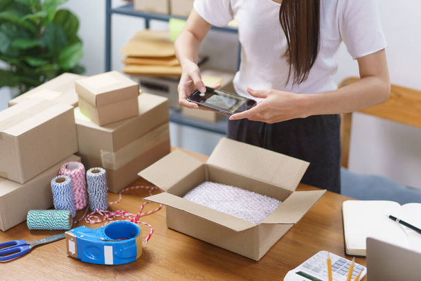 Online-Geschäftskonzept: Asiatische Geschäftsfrauen machen ein Foto, während sie Produkt in Paketbox verpacken. - Foto, Bild
