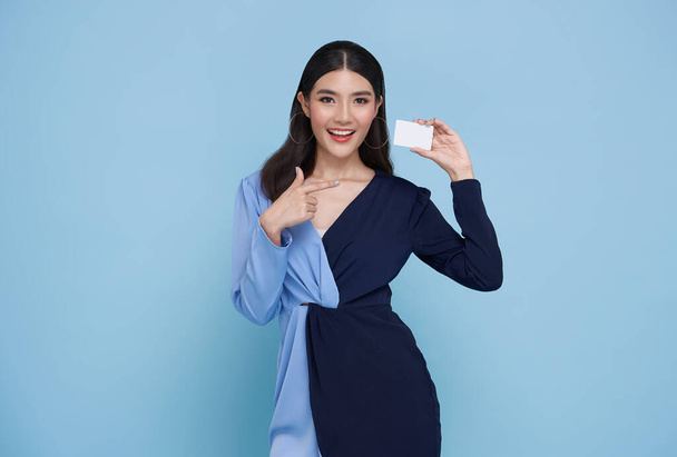 Mooie jonge Aziatische zakenvrouw glimlachen, tonen, presenteren mockup credit card voor online betaling geïsoleerd op blauwe achtergrond. - Foto, afbeelding