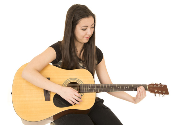 Cute girl playing her acoustic guitar sitting down - Foto, Imagen