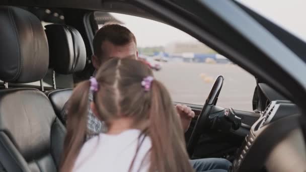 Ευτυχισμένος νεαρός πατέρας που βοηθάει την κόρη του να καθίσει στη θέση του συνοδηγού. Μεταφορές, ασφάλεια, οικογενειακή έννοια. Αργή κίνηση - Πλάνα, βίντεο