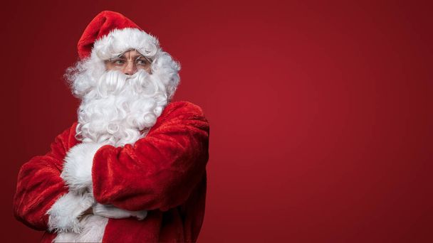 Zamyšlený Santa Claus se zkříženýma rukama uvažující o slavnostní sezóně - Fotografie, Obrázek