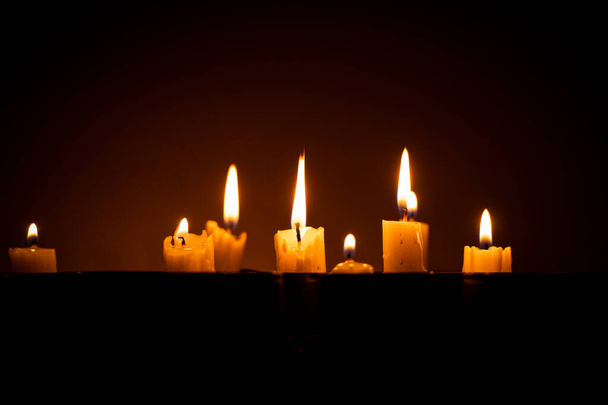 Brennende Kerzen stehen in abgebrannten Granatwerferhüllen im Dunkeln, Trauer um die Kriegstoten in der Ukraine - Foto, Bild