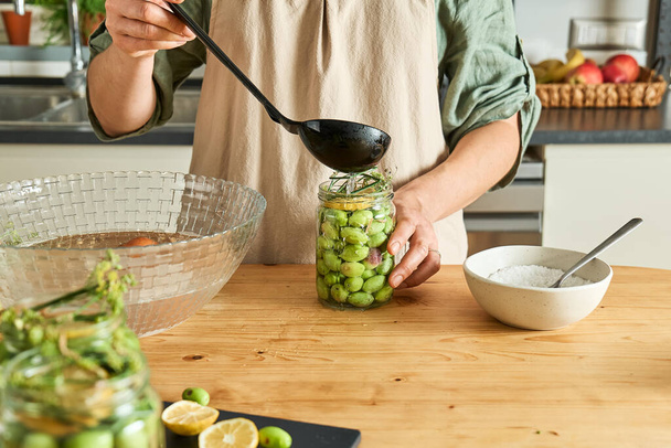 Donna che prepara olive fermentate in vaso di vetro con fette di limone, finocchio selvatico e salamoia in scatola. Inscatolamento di verdure di autunno. Cibo sano fatto in casa. Conservazione del raccolto. - Foto, immagini