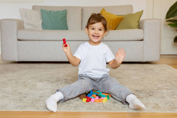 Концепция раннего развития. Маленькая девочка, играющая дома с учебными деревянными игрушками, милая счастливая девочка, развлекающаяся, сидя на полу в гостиной, копирующее пространство - Фото, изображение