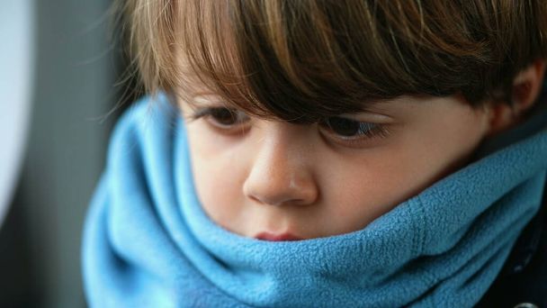 Primer plano de un niño contemplativo caucásico, encerrado en una bufanda, reflejando una profundidad de introspección, encapsulando un profundo estado meditativo - Foto, imagen