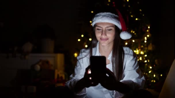 Νέα όμορφη ισπανόφωνη γυναίκα χρησιμοποιώντας smartphone γιορτάζει τα Χριστούγεννα στο σπίτι - Πλάνα, βίντεο