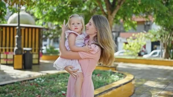 Mãe confiante, braços envoltos em torno de sua filha, sorrindo alegremente de pé no parque iluminado pelo sol, irradiando positividade e felicidade - Filmagem, Vídeo