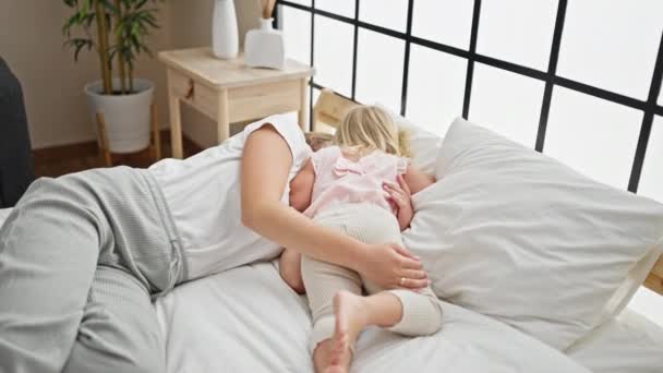 Przytulny poranny uścisk, zrelaksowana matka kaukaska i córeczka leżące na wygodnym łóżku, dzielące ciepłe uściski w ich sypialni - Materiał filmowy, wideo