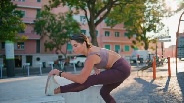 Uma senhora flexível a aquecer no ginásio urbano. Mulher confiante no sportswear esticando as pernas durante o treino de fitness na cidade de verão. Desportista de meia-idade se preparando para correr em local ao ar livre sozinho  - Filmagem, Vídeo