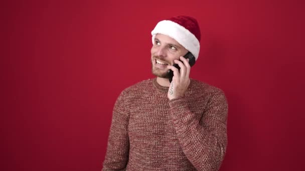 Fiatal fehér férfi mosolyog telefonon beszél izolált vörös háttér - Felvétel, videó