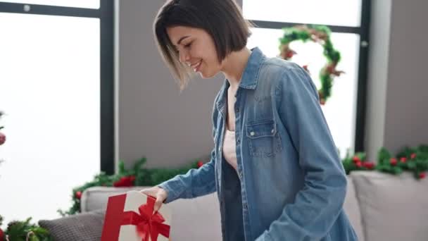 Mladý kavkazský žena uvedení dárek na vánoční strom doma - Záběry, video
