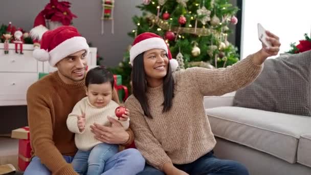 Pareja e hijo hacen selfie por teléfono inteligente sentado en el suelo por árbol de Navidad en casa - Metraje, vídeo