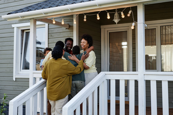 Portrait of happy black family embracing while standing on porch of new house, copy space - Photo, image