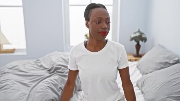 Mujer afroamericana temerosa, expresión disgustada en su cara, reacción de aversión evidente mientras se acuesta en su cama en el dormitorio - Imágenes, Vídeo