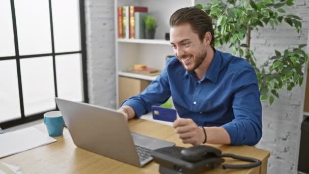 Młody Latynos człowiek biznes zakupy z laptopem i kartą kredytową świętuje w biurze - Materiał filmowy, wideo