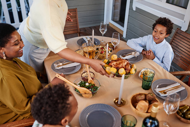 Família afro-americana feliz se reunindo na mesa de jantar ao ar livre em um ambiente acolhedor - Foto, Imagem