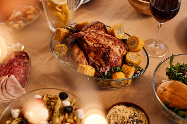 Close up of roasted chicken on dinner table with rustic homemade dishes in cozy setting - Photo, Image
