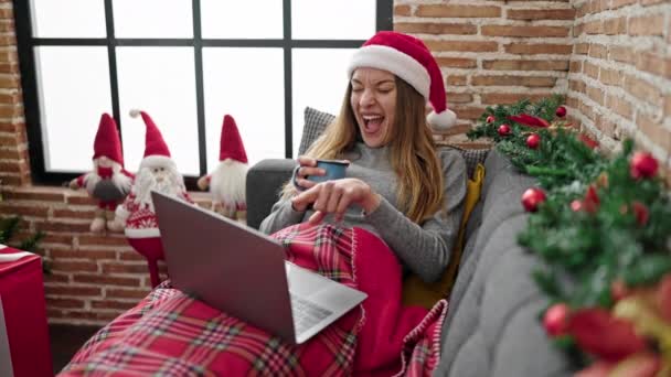 Joven mujer caucásica viendo la película bebiendo café celebrando la Navidad en casa - Metraje, vídeo