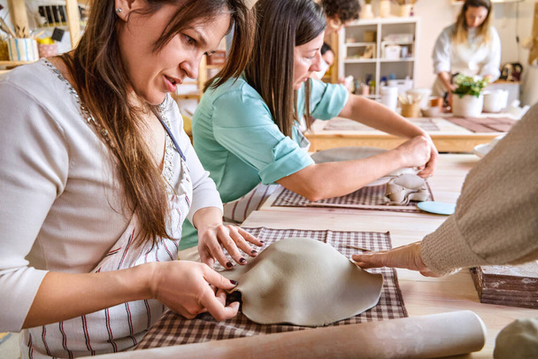 陶芸のクラスで工芸品を作っている間,女性は粘土を成形し,形作ります. クラフトと趣味のコンセプト. - 写真・画像