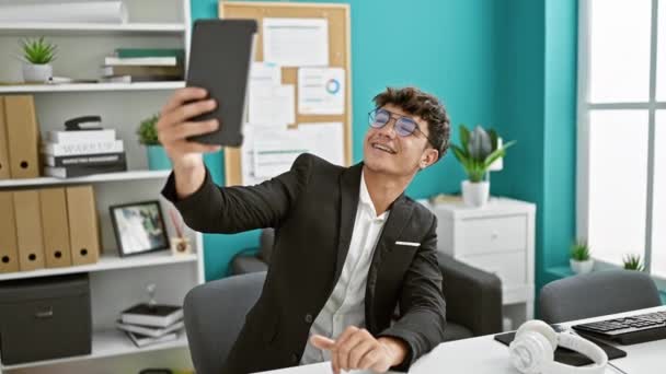 Knappe jonge Latijns-Amerikaanse tiener werkt in een bedrijf, het maken van een selfie op zijn laptop touchpad in het kantoor interieur. - Video