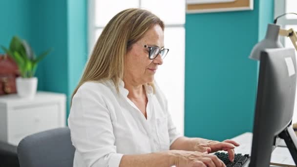 Orta yaşlı İspanyol iş kadını ofiste bilgisayar kullandığını vurguladı. - Video, Çekim