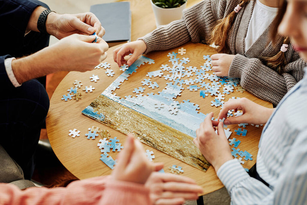 Close up of unrecognizable family playing jigsaw puzzle game together at home - Photo, Image