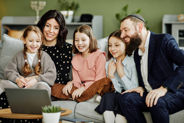 Ritratto della moderna famiglia ebrea che utilizza il computer portatile e chiama tramite videochat in un accogliente ambiente domestico - Foto, immagini