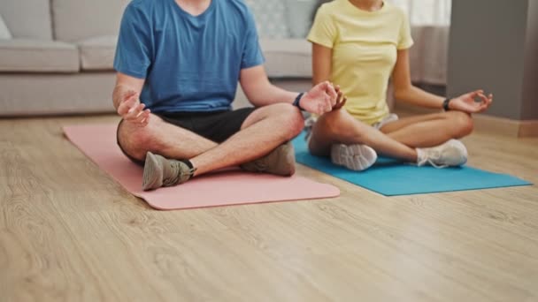 Mooi koppel, diep in de liefde, stretching hun atletische lichamen en omarmen een gezonde levensstijl door yoga training, samen zitten op de vloer van hun gezellige huis. - Video