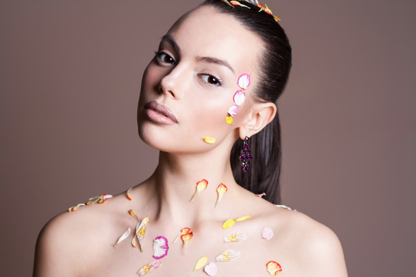 Young woman with flowers. Beauty girl with flower petals - Foto, imagen