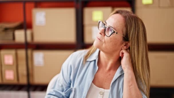 Orta yaşlı İspanyol kadın ecommerce iş işçisi masada oturuyor ve ofiste düşünüyor. - Video, Çekim
