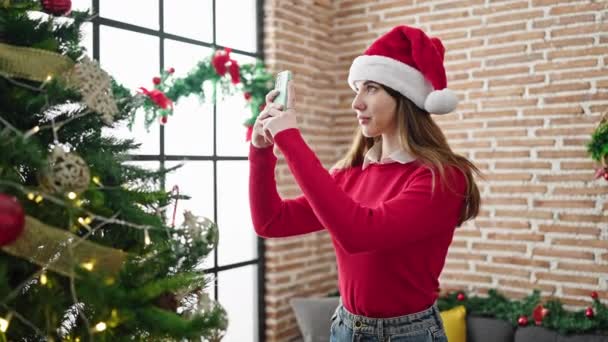 Mujer hispana joven tomando fotos al árbol de navidad en casa - Metraje, vídeo