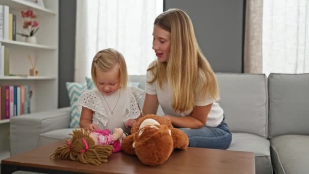Blanke moeder en dochter gelukkig genieten van ontspannen momenten thuis, speels zoenen terwijl ze comfortabel binnen zitten, omringd door speelgoed - Video