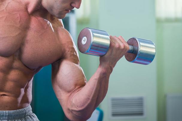 Handsome muscular man working out with dumbbells - Photo, Image