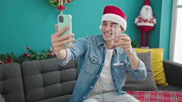 Молодий іспаномовний чоловік святкує різдвяні тости з шампанським на відеодзвінок вдома - Кадри, відео