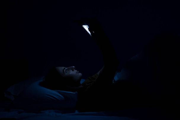 gyönyörű fiatal lány az ágyban fehér ágy és telefon. - Fotó, kép