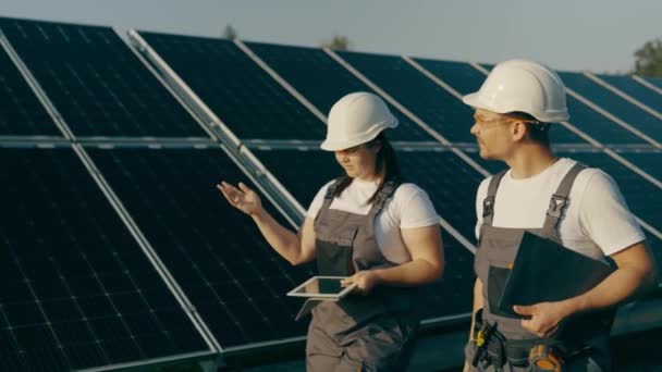 The chief engineer and specialist study the report on the results of the solar power plant while walking around the farm. Business team. Clean energy. Industry. High-quality 4K shooting - Footage, Video