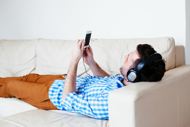 Человек лежит на диване и слушает музыку
 - Фото, изображение