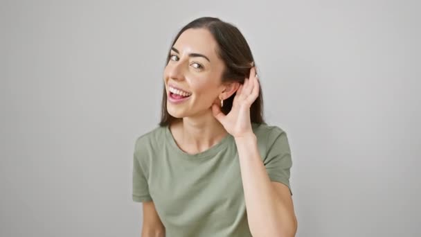Vibrant young hispanic woman in casual clothes strikes a gossip-listening gesture. exudes charm despite her deafness. isolated white background capturing every glint of secret rumors. - Footage, Video