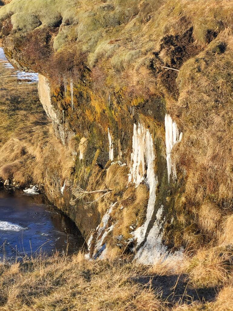 Σκανδιναβικό φαράγγι με ρυάκι ποταμού και καφετιές παγωμένες πλαγιές δημιουργώντας φυσικό τοπίο από την Ισλανδία. Όμορφο φαράγγι Fjadrargljufur με άγρια φύση στην Ισλανδία, φυσικό περιβάλλον. - Φωτογραφία, εικόνα