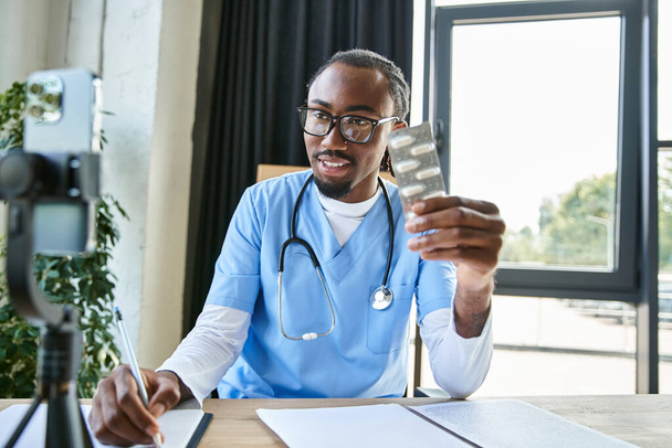 fröhlich attraktive afrikanisch-amerikanische Ärztin hält Tabletten in der Hand und macht sich Notizen, während sie telefonisch berät - Foto, Bild