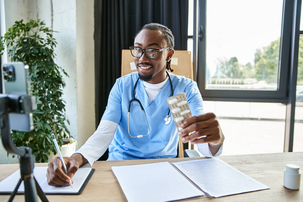 alegre atractivo afroamericano médico sosteniendo píldoras y tomando notas mientras consulta por teléfono - Foto, imagen